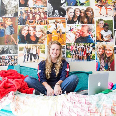 Student in dorm room sitting on her bed